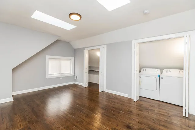 an empty room with wooden floor cabinet and windows