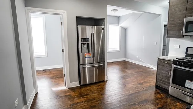 a kitchen with a refrigerator stove and wooden floor