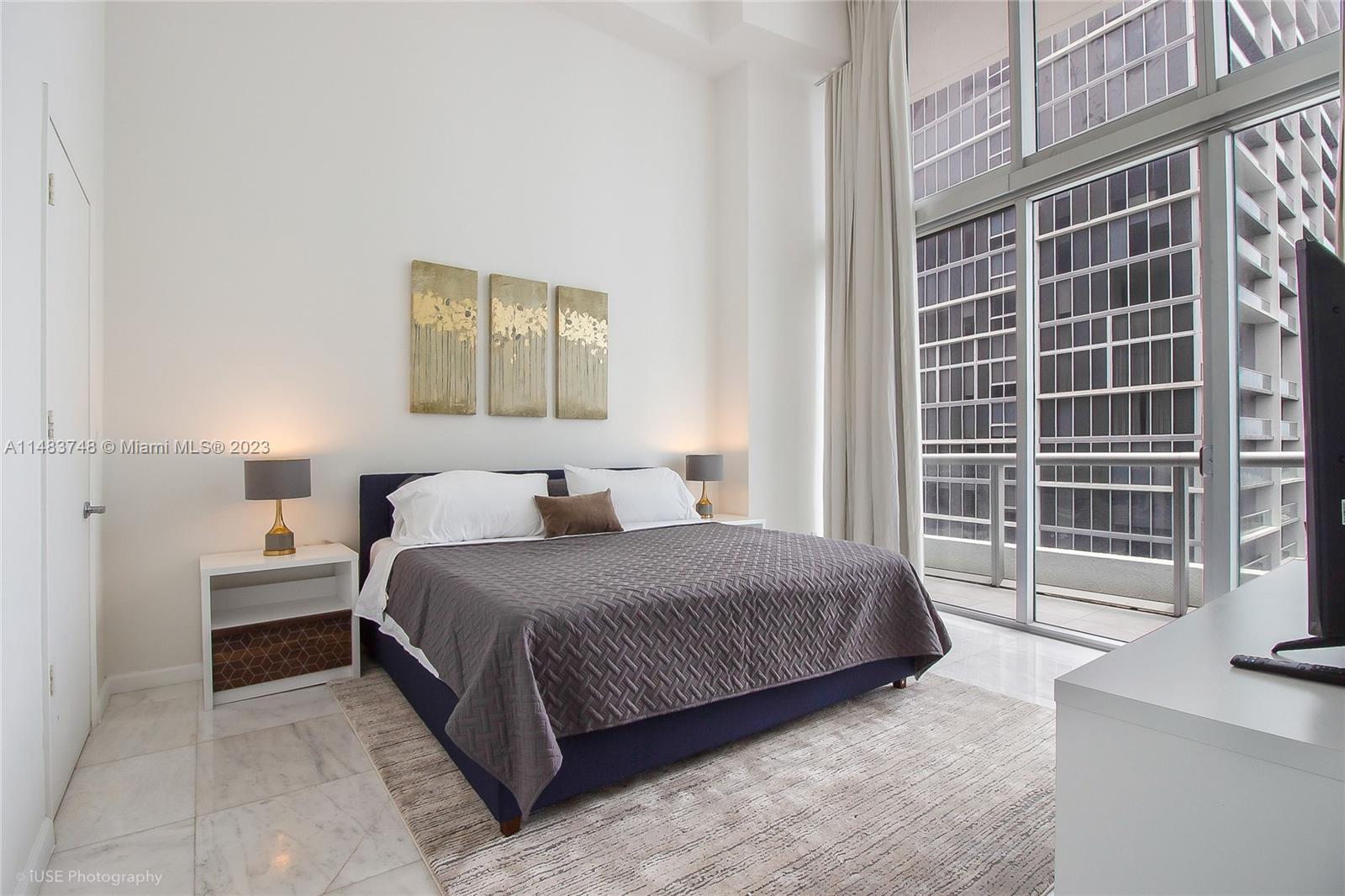 Brickell Miami, FL 33131 - Photo 7 of 10 a bedroom with a bed and table with windows