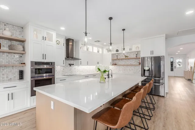 a kitchen with stainless steel appliances kitchen island granite countertop a table chairs stove and refrigerator