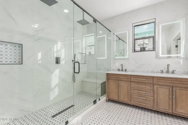 a bathroom with a double vanity sink a toilet a mirror and shower