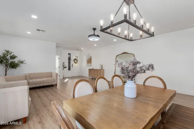 a dining room with wooden floor a chandelier a glass table and chairs