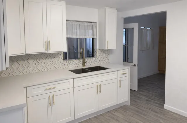a kitchen with white cabinets and sink