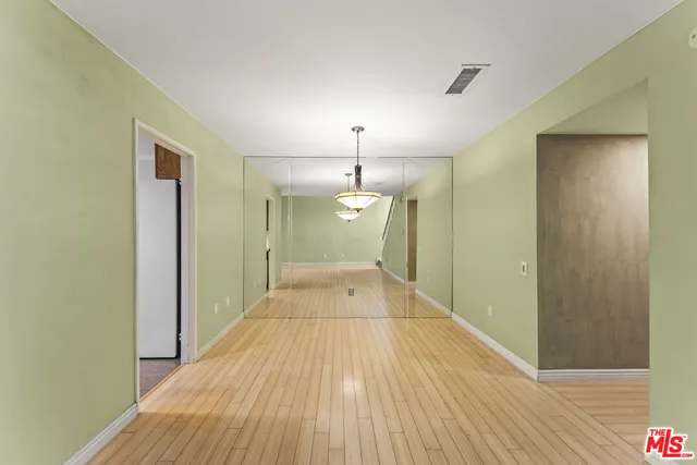 a view of a hallway with wooden floor and a bathroom