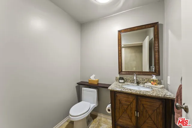 a bathroom with a granite countertop toilet sink and mirror