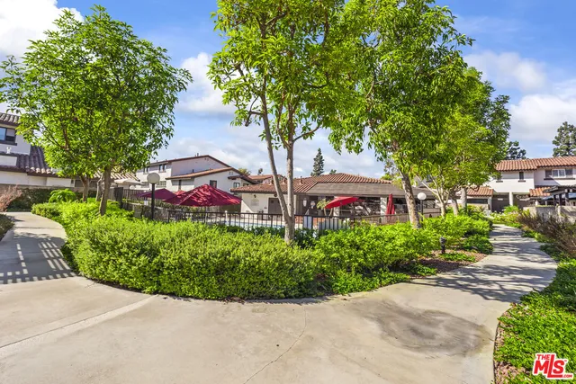 a view of a garden with a bench in front of the house