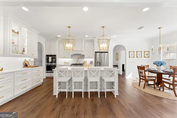 a kitchen with stainless steel appliances a dining table chairs and wooden floor
