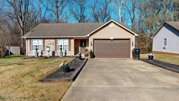 a view of house and yard with trees in the background