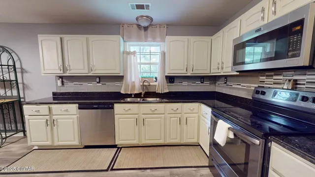 a kitchen with stainless steel appliances granite countertop a stove a sink and a microwave