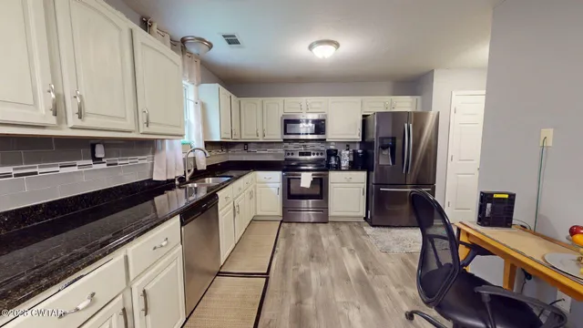 a kitchen with stainless steel appliances a refrigerator a sink a stove top oven a counter space and cabinets