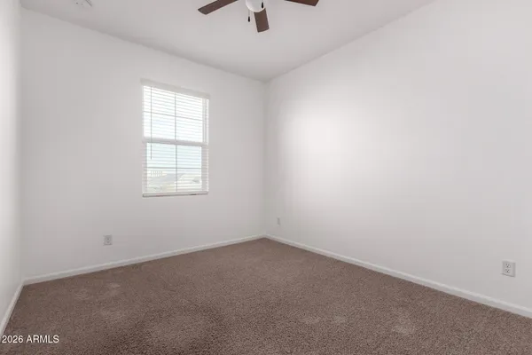 an empty room with a window and a ceiling fan