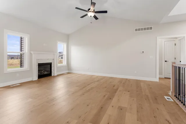 an empty room with windows fireplace and wooden floor