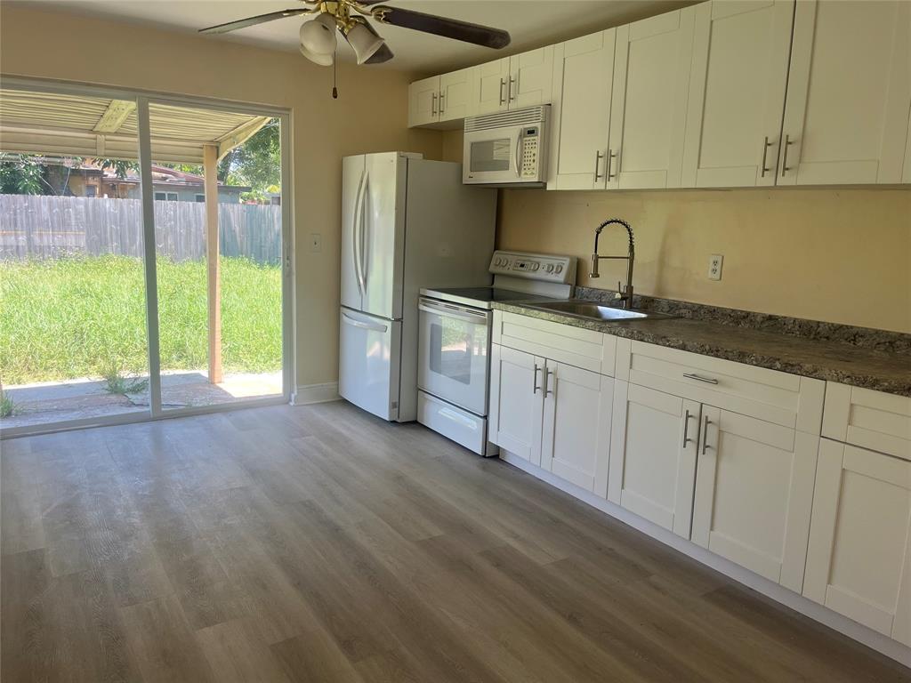 5641 Sheridan Street Hollywood, FL 33021 - Photo 9 of 13 a kitchen with granite countertop a refrigerator a sink and white cabinets