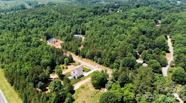 an aerial view of residential house with outdoor space and trees all around