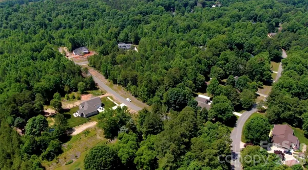 an aerial view of residential house with outdoor space and trees all around