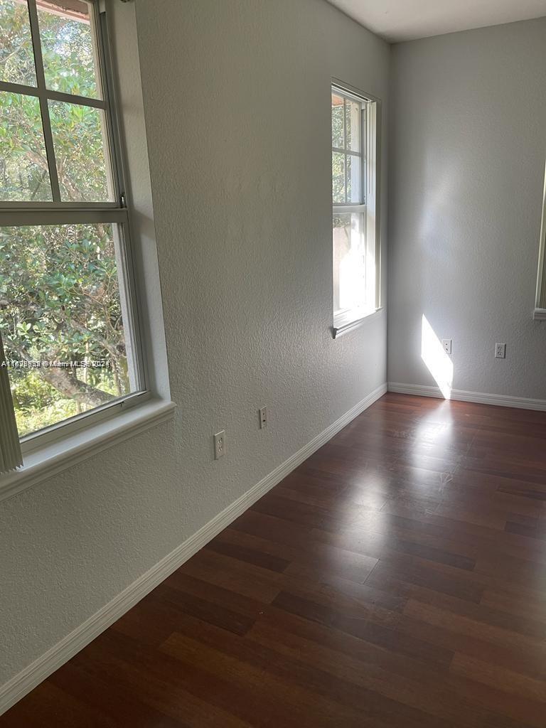 6912 West Sample Road, Unit 6912 Pompano Beach, FL 33063 - Photo 11 of 27 an empty room with wooden floor and windows