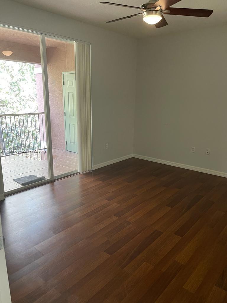 6912 West Sample Road, Unit 6912 Pompano Beach, FL 33063 - Photo 13 of 27 an empty room with wooden floor and windows