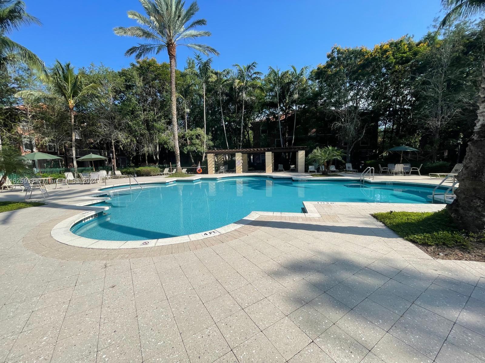 6912 West Sample Road, Unit 6912 Pompano Beach, FL 33063 - Photo 2 of 27 a view of a swimming pool with a yard