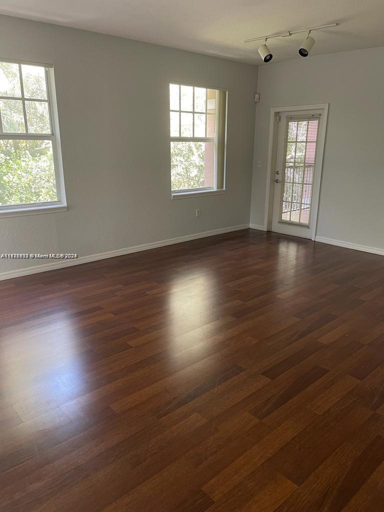 6912 West Sample Road, Unit 6912 Pompano Beach, FL 33063 - Photo 9 of 27 an empty room with wooden floor and windows