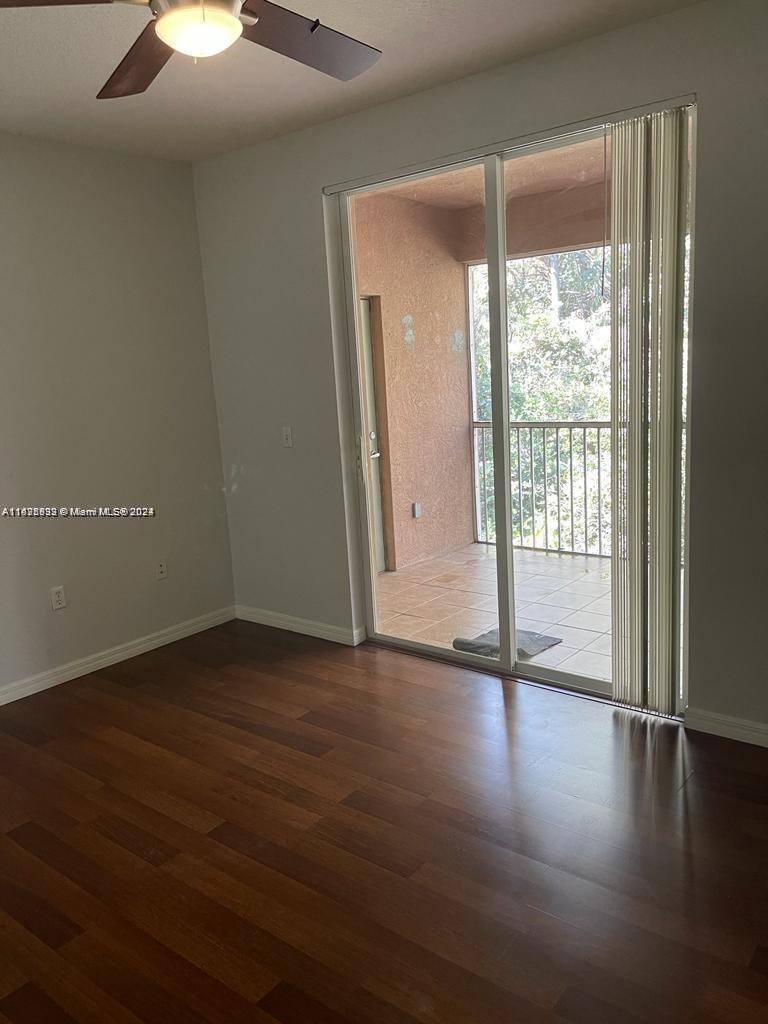 6912 West Sample Road, Unit 6912 Pompano Beach, FL 33063 - Photo 10 of 27 a view of an empty room with wooden floor and a window