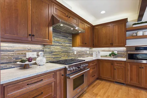 a kitchen with stainless steel appliances granite countertop a sink a stove cabinets and wooden floor
