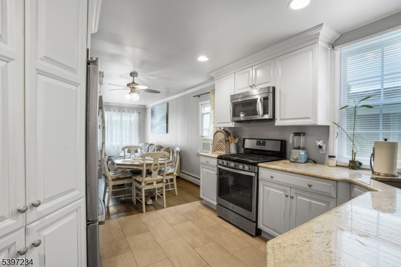 102 East Shore Road Denville, NJ 07834 - Photo 4 of 14 a kitchen with stainless steel appliances kitchen island granite countertop a stove top oven a sink a dining table and chairs