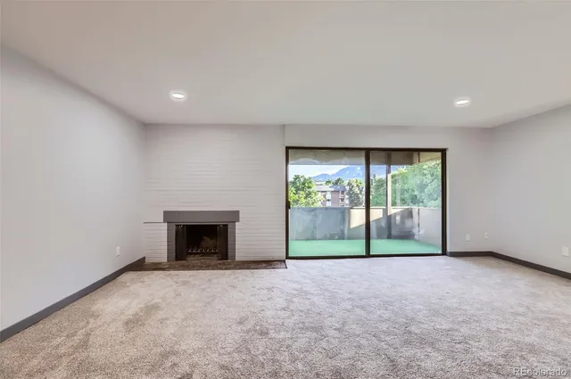 a view of an empty room with wooden floor and a fireplace