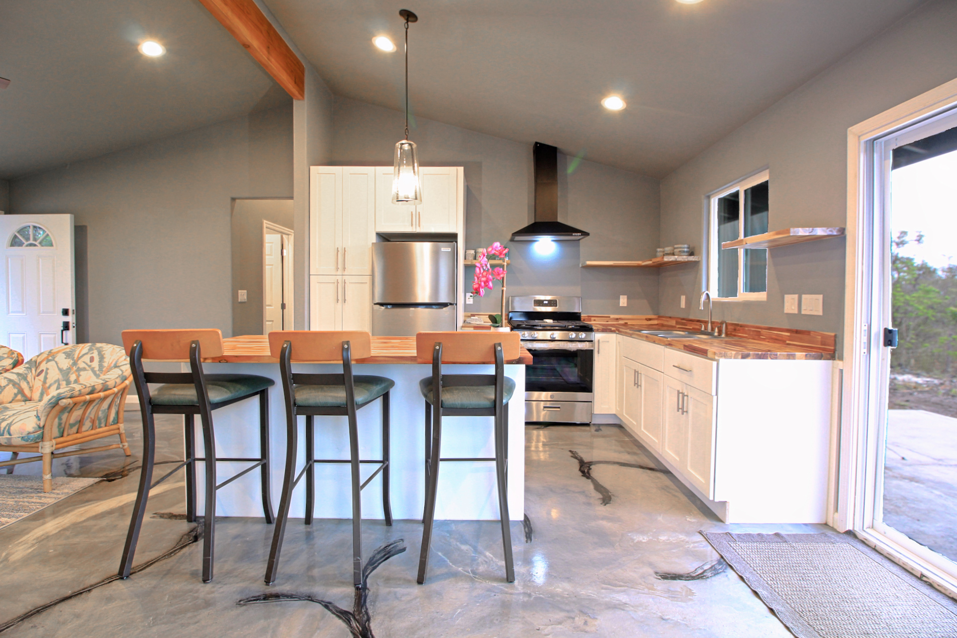 92-1920 Aloha Boulevard Ocean View, HI 96704 - Photo 15 of 26 a kitchen with stainless steel appliances kitchen island granite countertop a kitchen island a stove a table and chairs
