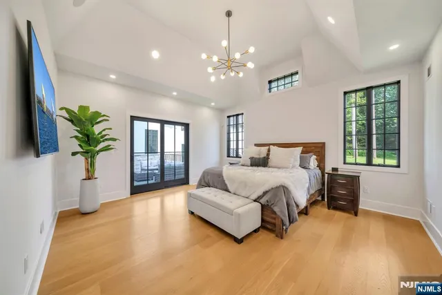 a spacious bedroom with a large bed chandelier and a window