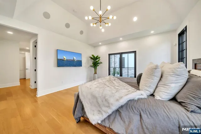 a spacious bedroom with a large bed a chandelier and a dresser