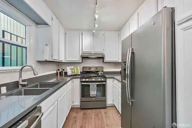 a kitchen with stainless steel appliances white cabinets a window and a sink