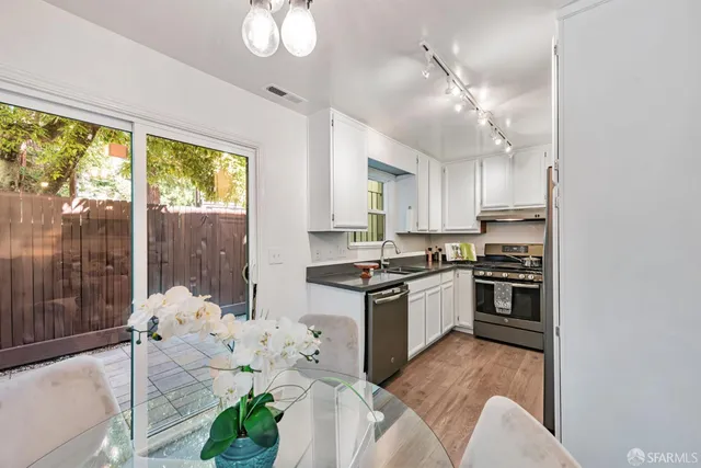 a kitchen with stainless steel appliances kitchen island granite countertop a refrigerator oven a stove a dining table and chairs with wooden floor