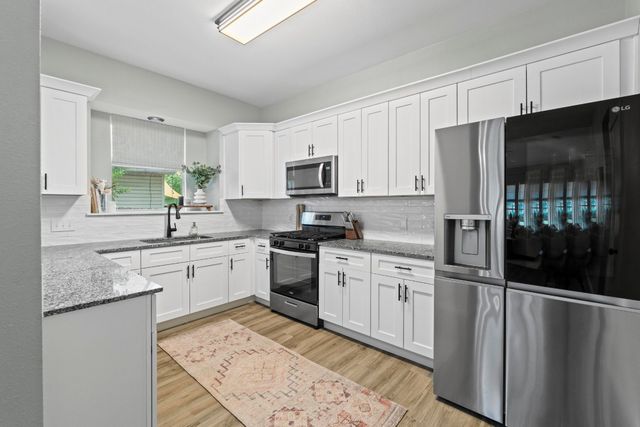 a kitchen with granite countertop a refrigerator stove top oven and sink