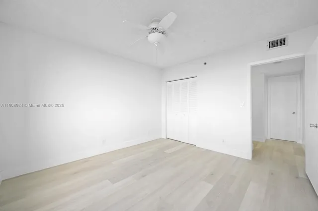 an empty room with a ceiling fan and wooden floor