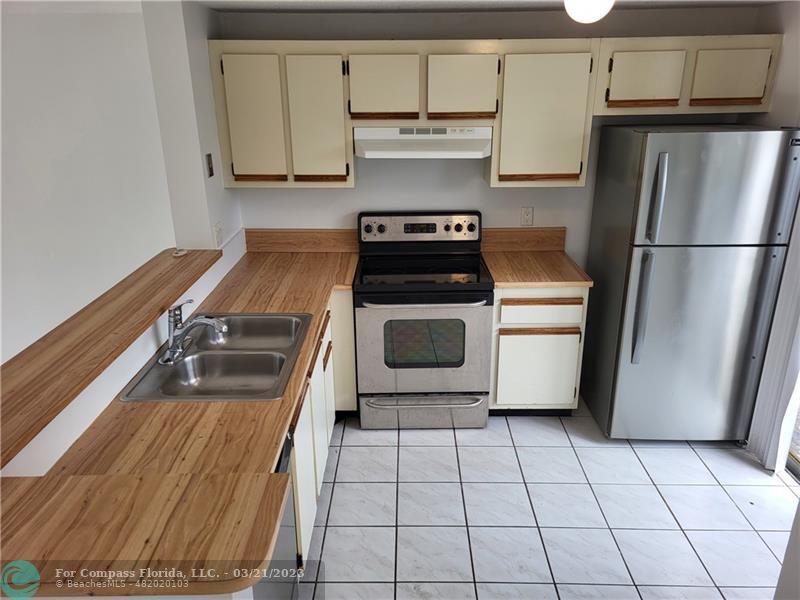 197 Southwest 3rd Street, Unit 197 Pompano Beach, FL 33060 - Photo 5 of 28 a kitchen with a stove top oven cabinets and stainless steel appliances