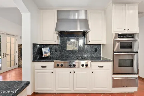 a kitchen with granite countertop a stove a microwave and cabinets