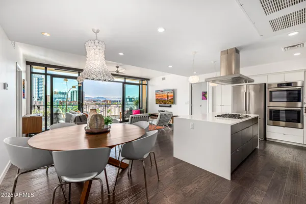 a kitchen with stainless steel appliances a dining table chairs stove and white cabinets