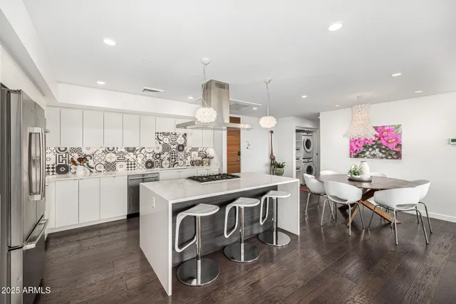 a kitchen with stainless steel appliances kitchen island granite countertop a refrigerator a stove a sink dishwasher and white cabinets with wooden floor