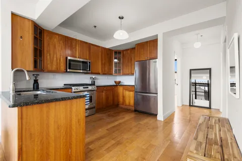 a kitchen with granite countertop stainless steel appliances a refrigerator a stove top oven a sink dishwasher and wooden cabinets