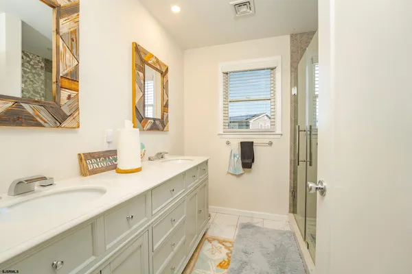 a bathroom with a granite countertop sink a mirror and a shower