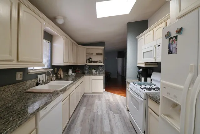 a kitchen with granite countertop a sink stove and cabinets