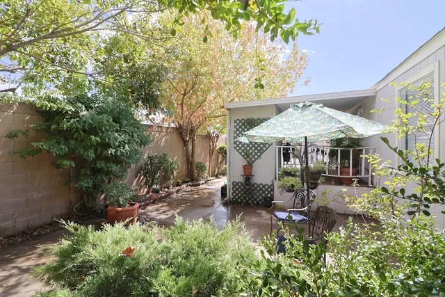 a backyard of a house with table and chairs under an umbrella
