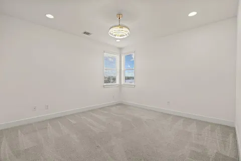 an empty room with windows and chandelier fan