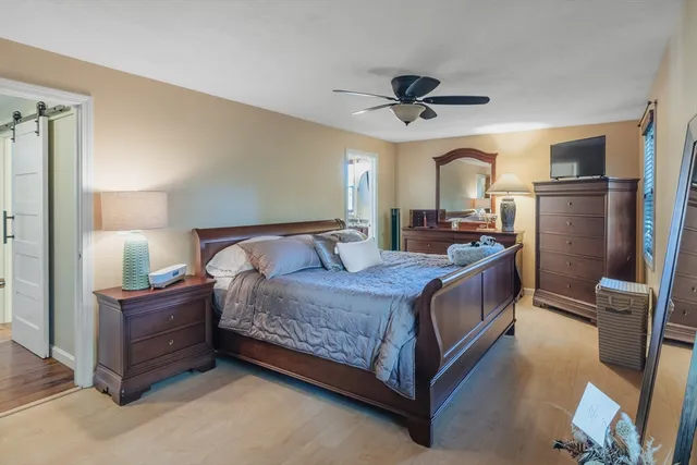 a bedroom with a bed wooden floor and ceiling fan