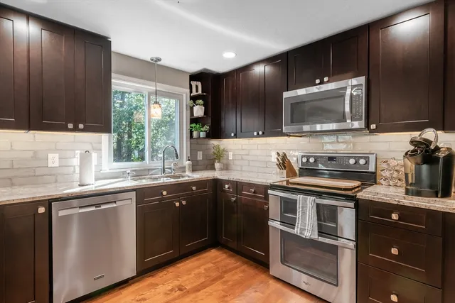 a kitchen with stainless steel appliances granite countertop a stove a sink dishwasher and a microwave oven with cabinets