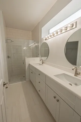 a bathroom with a double vanity sink mirror and shower