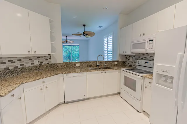 a kitchen with granite countertop white cabinets and white appliances