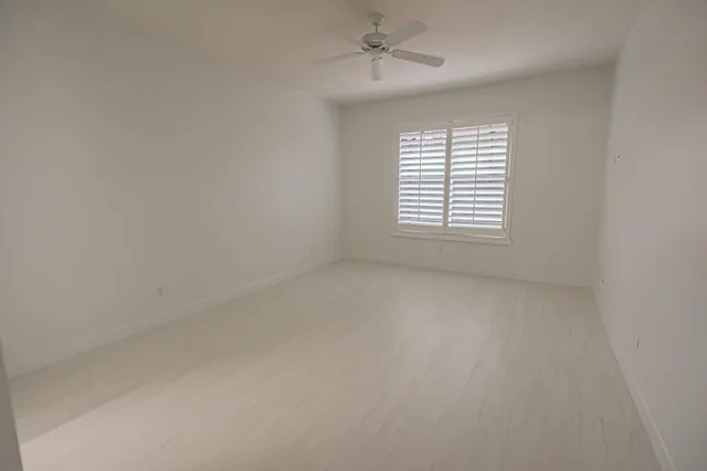 an empty room with a window and a ceiling fan