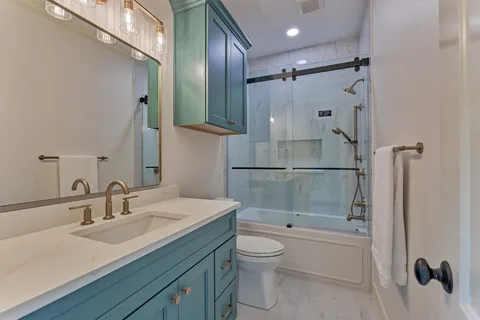 a bathroom with a granite countertop sink toilet and shower