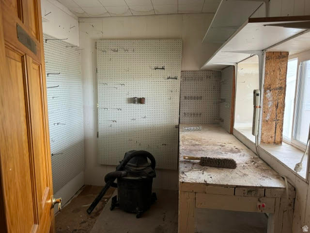 1124 Washam Road Green River, WY 82938 - Photo 28 of 35 Workshop space featuring extensive pegboard storage, a built-in workbench, an upper storage shelf, and natural light from a window